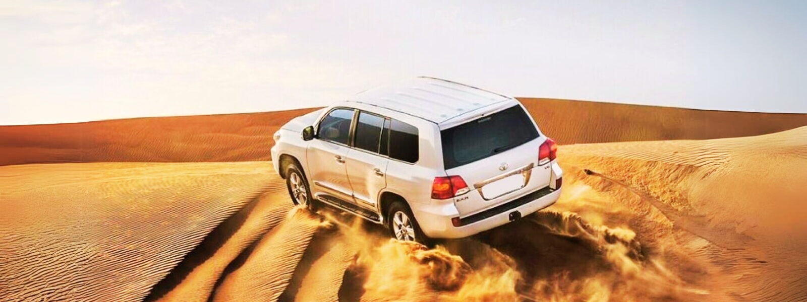 A white SUV driving through the desert under a clear blue sky.