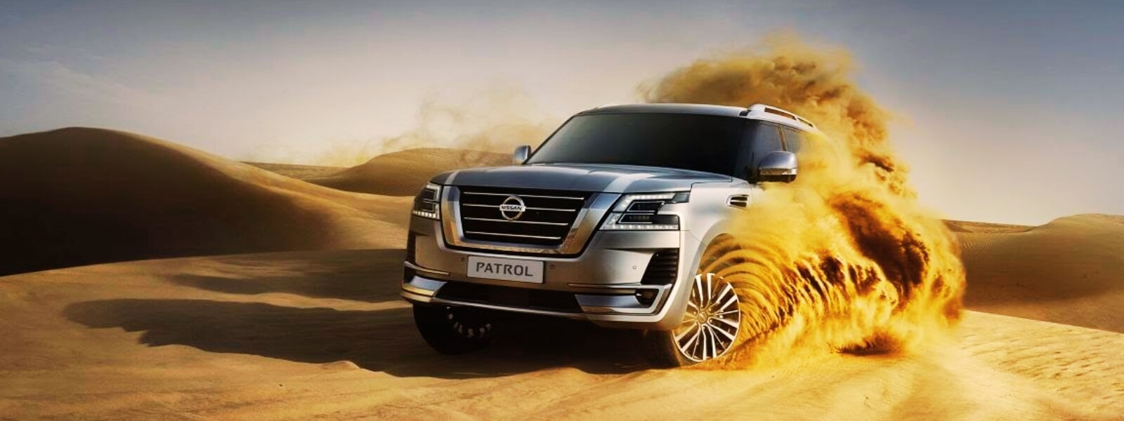 An SUV navigating through sandy dunes in the desert.