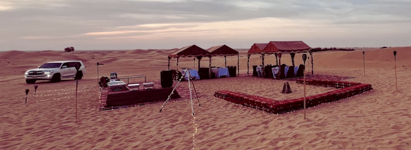 A private tent setup in the desert with a car parked nearby.