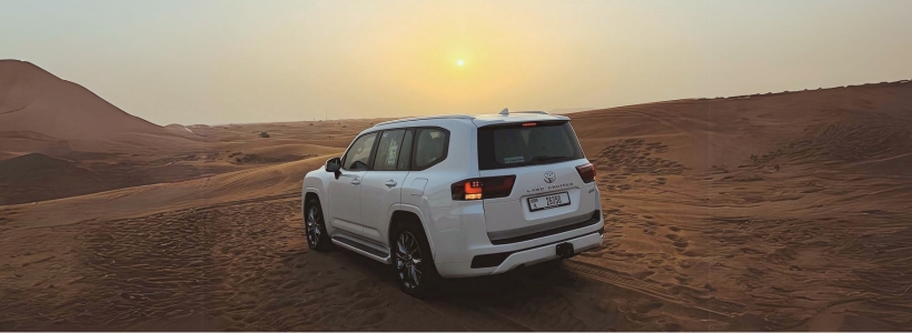 A white SUV driving through the desert at sunset, showcasing the vastness and tranquility of the landscape.