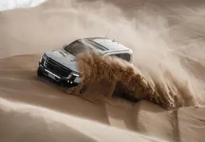 A 4X4 vehicle is navigating through sandy dunes in the desert.