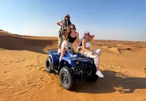 Women having fun on an ATV Quad bike in the sandy desert terrain.