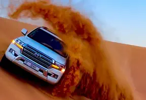 A Toyota Land Cruiser 4x4 driving through the desert on a safari adventure.