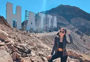 A woman posing and smiling in front of the Hatta sign.