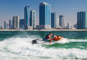 A man on a jet ski gliding through the water, with a stunning city skyline in the background.