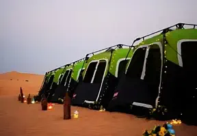 Desert campsite with tents and candlelight.