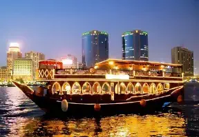A dhow sailing on water with a city skyline in the background, showcasing the beauty of urban and natural elements.